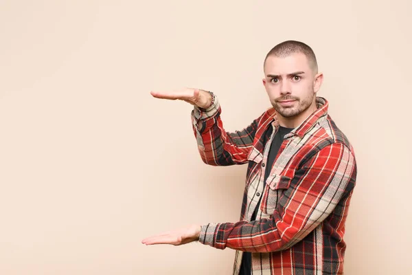 Joven Hombre Guapo Sosteniendo Objeto Con Ambas Manos Espacio Copia — Foto de Stock