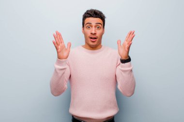 Gri duvara karşı inanılmaz bir şey fark ettiğinde genç Arap adam şaşkın ve şaşırmış görünüyordu.