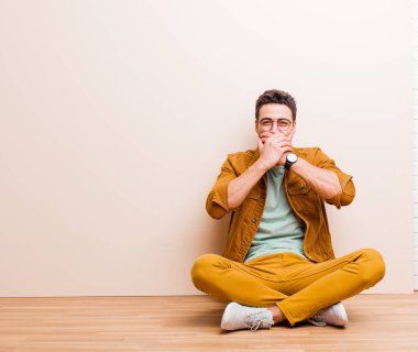 Genç Arap bir adam şok olmuş, şaşırmış bir ifadeyle ağzını kapatıyor. Sır saklıyor ya da 