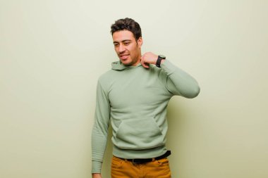 Genç Arap bir adam stresli, endişeli, yorgun ve hayal kırıklığına uğramış, gömleğini çekmiş, düz duvara karşı sorunlu görünüyor.