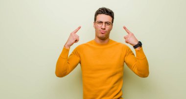 Kötü tavırlı genç bir Arap adam gururlu ve agresif görünüyor, yukarı bakıyor ya da duvara yaslanmış ellerle alay ediyor.