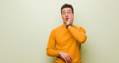 Genç Arap adam şok olmuş ve şaşkınlık içinde yüz yüze ağzı açık bir şekilde duvara yaslanmış inanamadığını söylüyor.