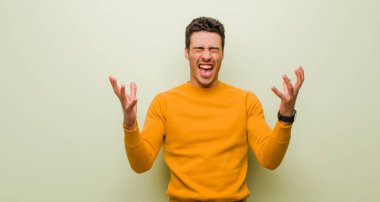 Genç Arap adam öfkeyle bağırıyor, stres altında ve elleri havada neden düz duvara yaslandığımı söylüyor.