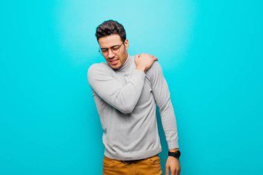 Genç Arap adam yorgun, stresli, endişeli, hayal kırıklığına uğramış ve depresif hissediyor. Sırtı ya da boynu düz duvarda ağrıyor.