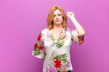 Orta yaşlı kadın ciddi, güçlü ve isyankar hissediyor, yumruğunu kaldırıyor, protesto ediyor ya da devrim için savaşıyor.