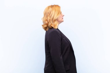 Profil görünümlü orta yaşlı kadın ileriyi kopyalamak istiyor, düşünüyor, hayal ediyor ya da hayal kuruyor.