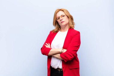 Orta yaşlı bir kadın mutsuz ve hayal kırıklığına uğramış, ciddi görünüyor, kızgın ve kollarını kavuşturmuş.