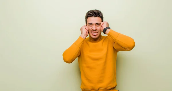 Młody Arabski Mężczyzna Wygląda Wściekłego Zestresowanego Rozdrażnionego Zakrywając Uszy Ogłuszającym — Zdjęcie stockowe