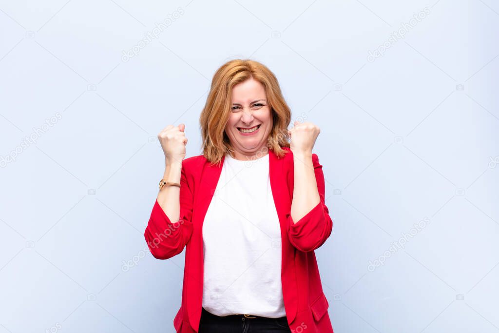 middle age woman shouting triumphantly, laughing and feeling happy and excited while celebrating success