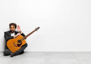 Genç müzisyen ciddi ve meraklı görünüyor, dinliyor, gizli bir konuşma veya dedikodu duymaya çalışıyor, gitar, rock 'n roll konseptiyle kulak misafiri oluyor.