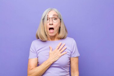 Yaşlı ya da orta yaşlı güzel bir kadın şok olmuş ve şaşırmış hissediyor, gülümsüyor, el ele tutuşuyor, mutlu oluyor ya da minnettarlık gösteriyor.