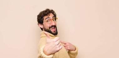 Genç havalı adam gururlu, kaygısız, kendinden emin ve mutlu, parmakları düz duvara değmiş bir şekilde gülümsüyor.