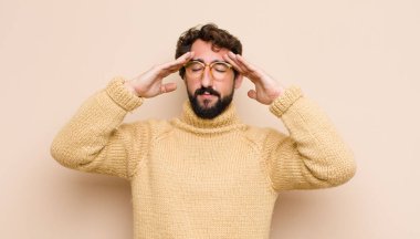 Genç havalı adam konsantre, düşünceli ve ilham verici görünüyor, beyin fırtınası yapıyor ve düz duvara karşı eller ve hayal kuruyor.