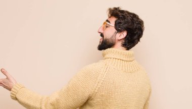 Genç havalı adam gülümsüyor, seni selamlıyor ve başarılı bir anlaşma için el sıkışmayı teklif ediyor, düz duvara karşı işbirliği kavramı.