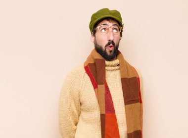 Genç havalı sakallı adam şok olmuş, mutlu, şaşkın ve şaşırmış hissediyor, ağzı açık bir şekilde yana bakıyor.