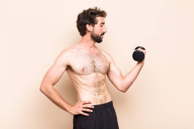 Genç havalı sakallı adam dambıl kaldırıyor. fitness konsepti