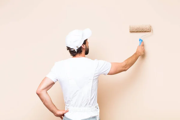 young painter bearded man painting a wall with a apint roller