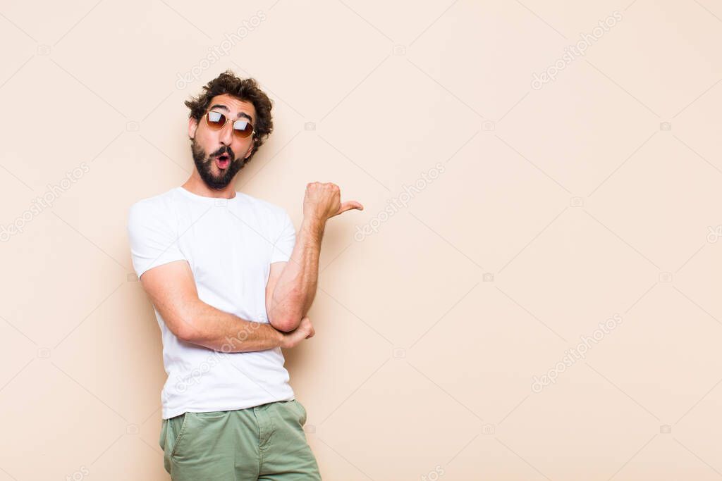 young cool bearded man surprised and pointing to the side