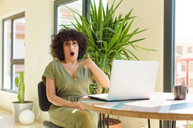 Evde dizüstü bilgisayarla çalışan genç bir Arap kadın.