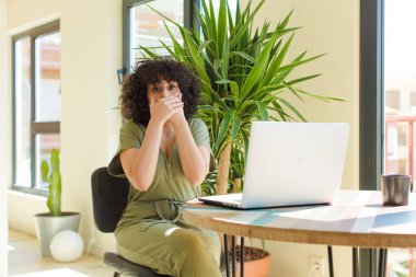 Evde dizüstü bilgisayarla çalışan genç bir Arap kadın.