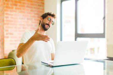 Dizüstü bilgisayarı olan genç sakallı adam seni selamlıyor ve başarılı bir anlaşma için el sıkışmayı teklif ediyor.