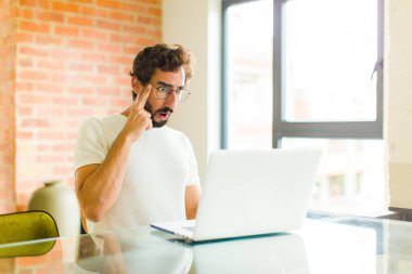 Dizüstü bilgisayarı olan genç sakallı adam şaşırmış, ağzı açık, şok olmuş, yeni bir düşünce, fikir ya da konsept keşfediyor.