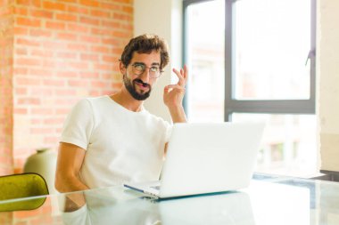 Dizüstü bilgisayarı olan genç sakallı bir adam sıkıcı, sıkıcı ve sıkıcı bir işin ardından sıkılmış, hayal kırıklığına uğramış ve uykulu hissediyor.