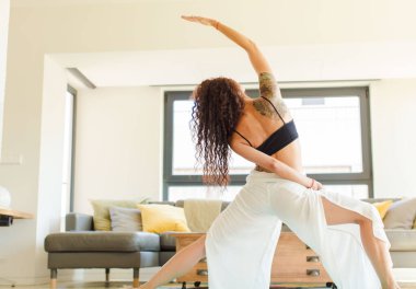 Evde yoga yapan genç ve güzel bir kadın. Evde dinlenme ve antrenman.