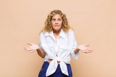 Orta yaşlı kadın şaşkın ve şaşkın hissediyor, şüpheci, farklı seçenekleri tartıyor veya komik bir ifadeyle seçiyor.