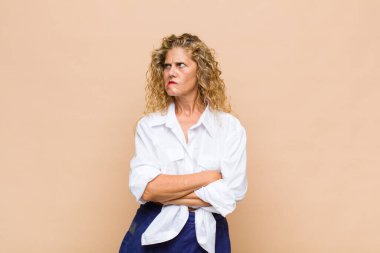 Orta yaşlı bir kadın şüpheye düşüyor ya da düşünüyor, dudağını ısırıyor ve kendini güvensiz ve gergin hissediyor, kenarda yer arıyor.