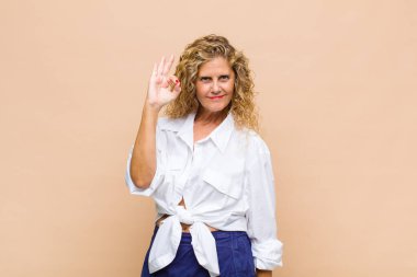 Orta yaşlı bir kadın mutlu, rahat ve tatmin olmuş hissediyor. Onayını iyi bir hareketle gösteriyor.