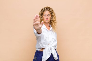 Orta yaşlı bir kadın ciddi, sert, hoşnutsuz ve kızgın görünüyor.