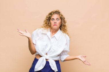 Orta yaşlı kadın şaşkın, kafası karışmış ve stresli görünüyor, farklı seçenekler arasında merak ediyor, kararsız hissediyor.