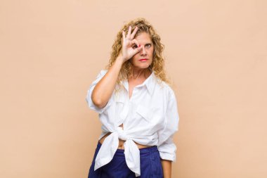 Orta yaşlı bir kadın mutlu bir şekilde gülümsüyor, şaka yapıyor ve gözetleme deliğinden bakıyor, sırları gözetliyor.