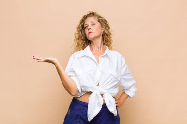 Orta yaşlı kadın gülümsüyor, kendinden emin, başarılı ve mutlu hissediyor, fotokopi alanında fikir veya konsept gösteriyor.