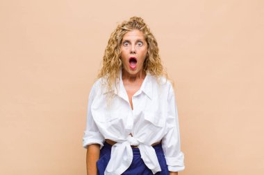 Orta yaşlı bir kadın şok olmuş ya da şaşırmış görünüyor, ağzı açık bir şekilde 