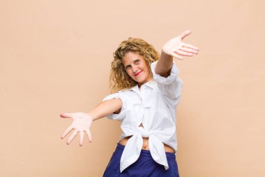 Orta yaşlı bir kadın neşeyle gülümsüyor sıcak, dostça, sevgi dolu bir kucak veriyor, mutlu ve sevimli hissediyor.