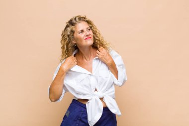 Orta yaşlı bir kadın stresli, endişeli, yorgun ve hayal kırıklığına uğramış, gömleğini çekmiş, sorunlu görünüyor.