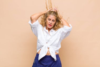 Orta yaşlı bir kadın üzgün, hayal kırıklığına uğramış, gergin ve bunalımda, yüzünü iki eliyle kapatıyor, ağlıyor.