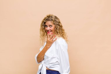 Orta yaşlı bir kadın gülümsüyor ve arkadaş canlısı görünüyor. Elleri önde, geriye doğru sayıyor.