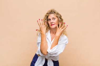 Orta yaşlı bir kadın gülümsüyor ve arkadaş canlısı görünüyor. 9 ya da 9 numarayı gösteriyor. Eli önde, geriye doğru sayıyor.