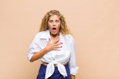 Orta yaşlı kadın şaşkın, şaşkın ve şaşırmış hissediyor, elleri göğsünde ve ağzı açık, kim olduğunu söylüyor, ben mi??