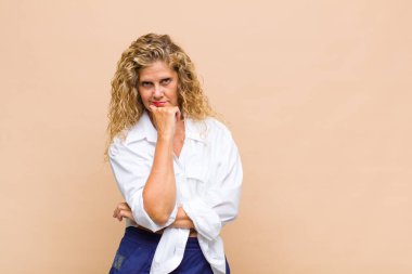 Orta yaşlı kadın gülümsüyor, hayattan zevk alıyor, mutlu, arkadaş canlısı, tatmin olmuş ve tasasız.