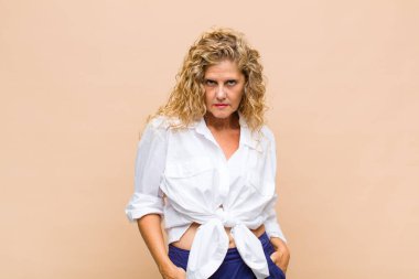 Orta yaşlı bir kadın gururlu, kendinden emin, havalı, küstah ve küstah görünüyor, gülümsüyor, başarılı hissediyor.