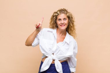 Orta yaşlı kadın mutlu bir şekilde gülümsüyor, tek eliyle boşluğu dolduruyor.