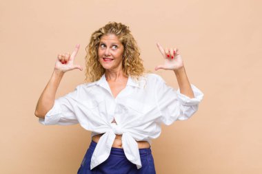 Orta yaşlı bir kadın iki eliyle kendi gülüşünü çiziyor, olumlu ve mutlu görünüyor, sağIık kavramı