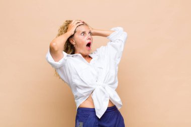 Orta yaşlı, ağzı açık bir kadın korkunç ve şok olmuş görünüyor. Korkunç bir hata yüzünden, el ele tutuşuyor.