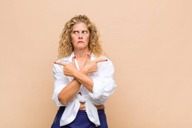 Orta yaşlı kadın şaşkın ve şaşkın görünüyor, güvensiz ve şüpheyle zıt yönleri işaret ediyor.