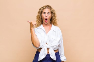 Orta yaşlı kadın inançsızlıktan şaşkın şaşkın bakıyor, yan taraftaki objeyi işaret ediyor ve diyor ki: