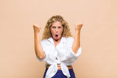 Orta yaşlı bir kadın inanılmaz bir başarıyı kutluyor. Kazanan gibi, heyecanlı ve mutlu görünüyor.!